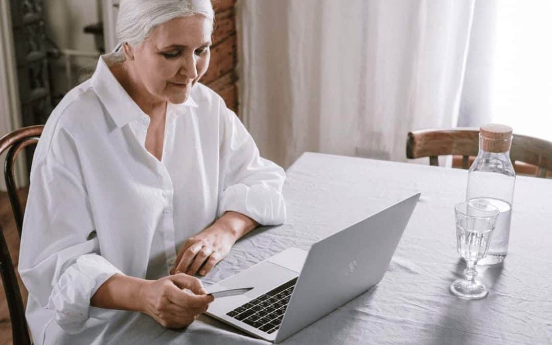 an older woman is shopping online on her laptop.